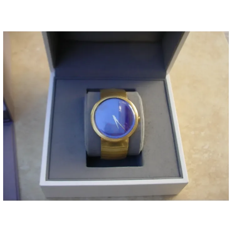 Gold watch with blue face in a box on a beige surface