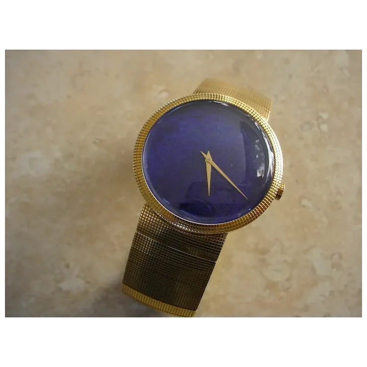 Gold wristwatch with a blue face on a beige surface