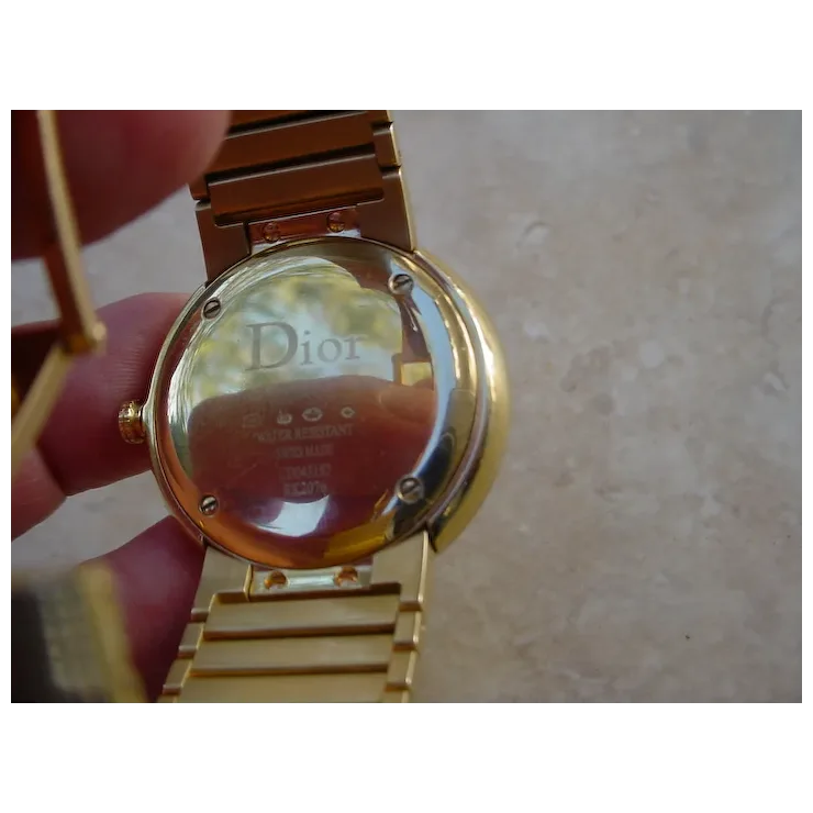 Gold watch with Dior branding on a neutral background