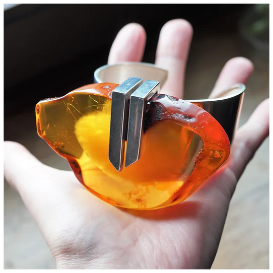 Hand holding a transparent amber-colored object with a metallic center