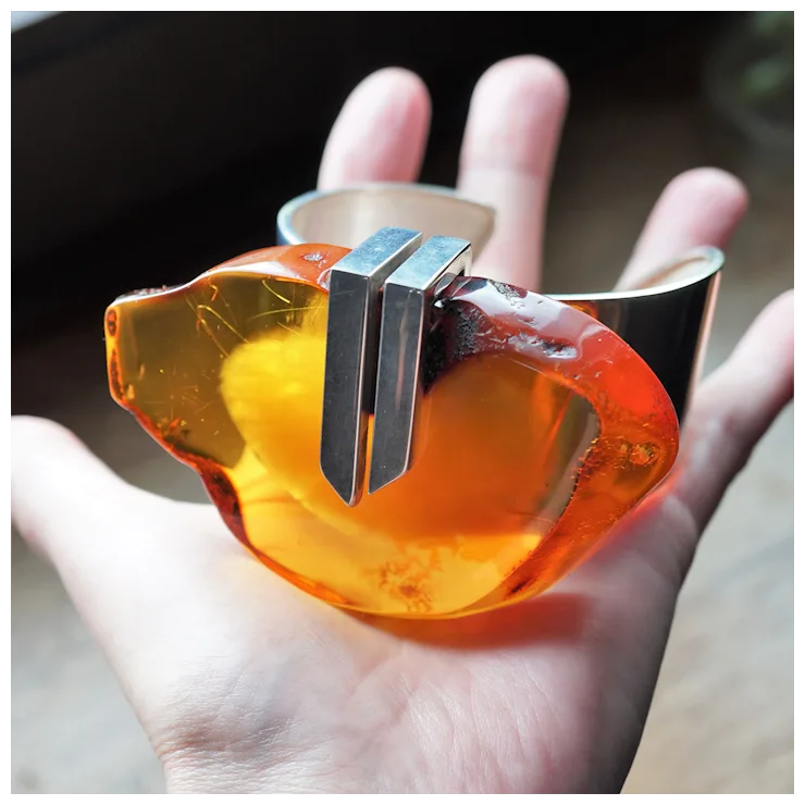 Hand holding a transparent amber-colored object with a metallic center