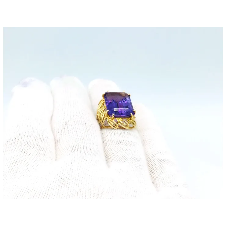 Gold ring with a purple gemstone on a light blue background