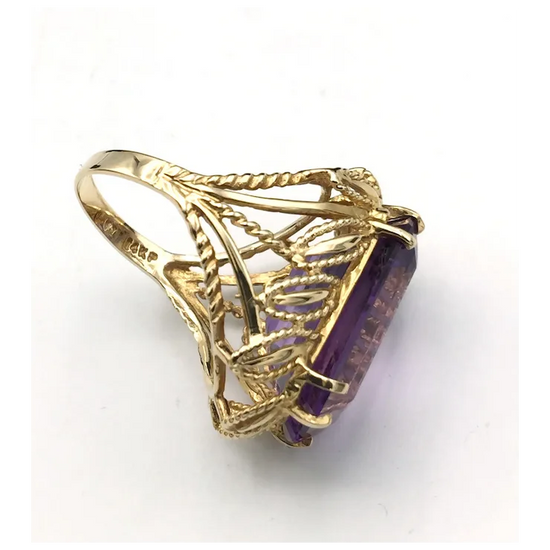 Gold ring with a purple gemstone on a white background