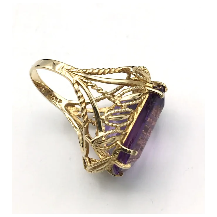Gold ring with a purple gemstone on a white background