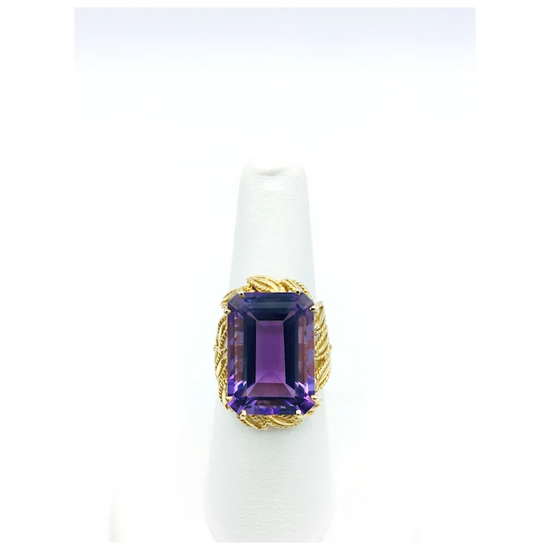 Ring with purple gemstone and gold band on a white background