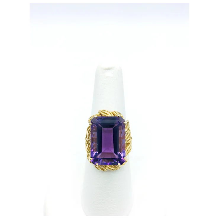 Ring with purple gemstone and gold band on a white background