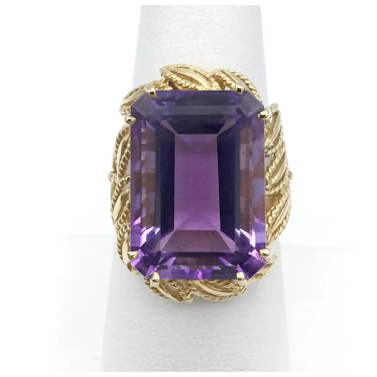 Gold ring with a large purple gemstone on a white background