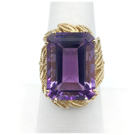 Gold ring with a large purple gemstone on a white background