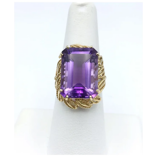 Gold ring with a purple gemstone on a white background