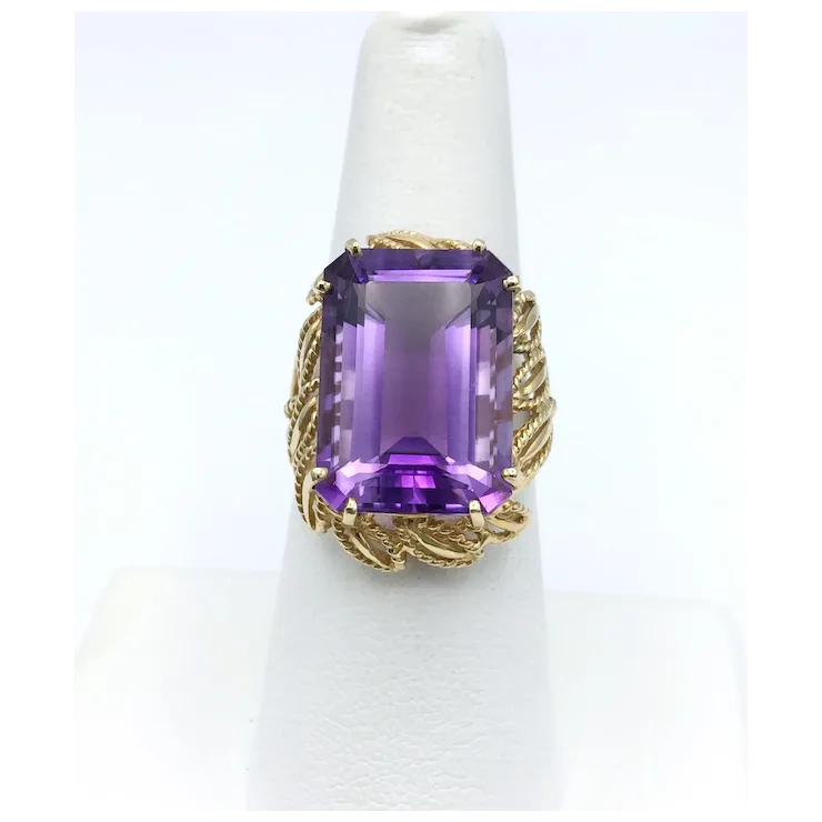 Gold ring with a purple gemstone on a white background