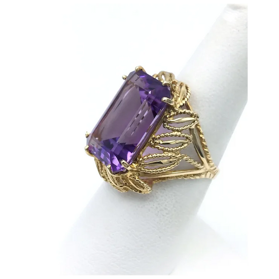 Gold ring with a large purple gemstone on a white background