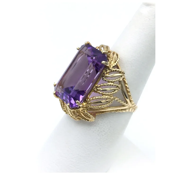 Gold ring with a large purple gemstone on a white background