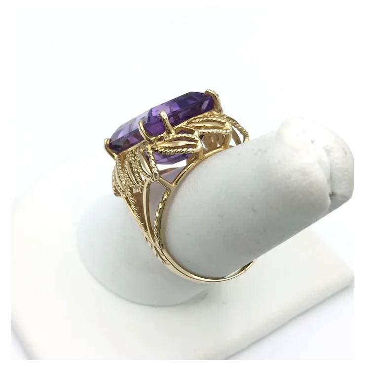 Gold ring with a purple gemstone on a white stand