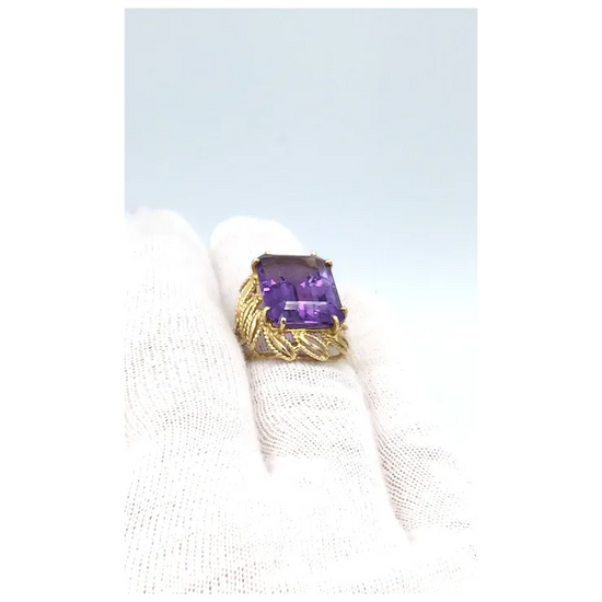 Gold ring with a purple gemstone on a white background