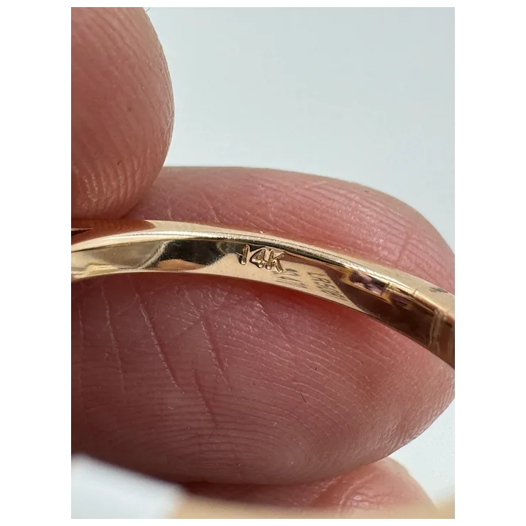 Gold ring being held between fingers with a clear background