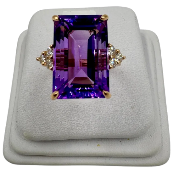 Ring with purple gemstone and gold accents on a white background