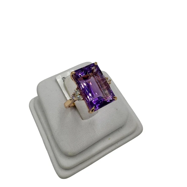 Purple gemstone ring on a white stand with a white background