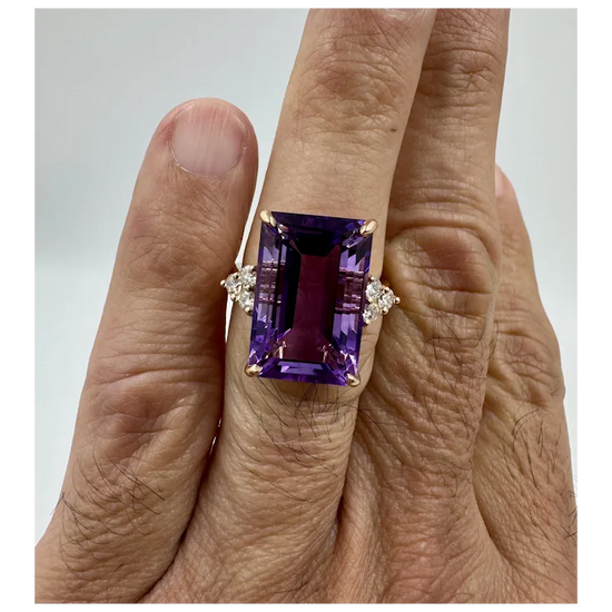 Amethyst ring with diamond accents on a finger against a neutral background