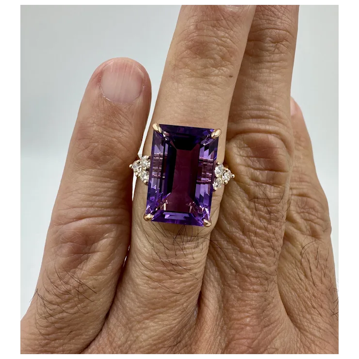 Amethyst ring with diamond accents on a finger against a neutral background