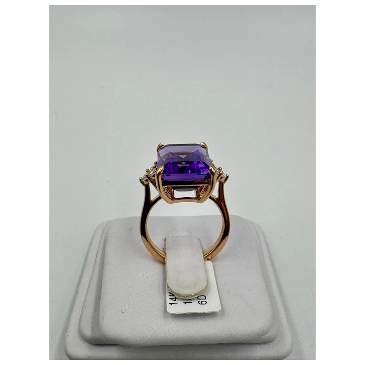 Rose gold ring with a purple gemstone on a gray background