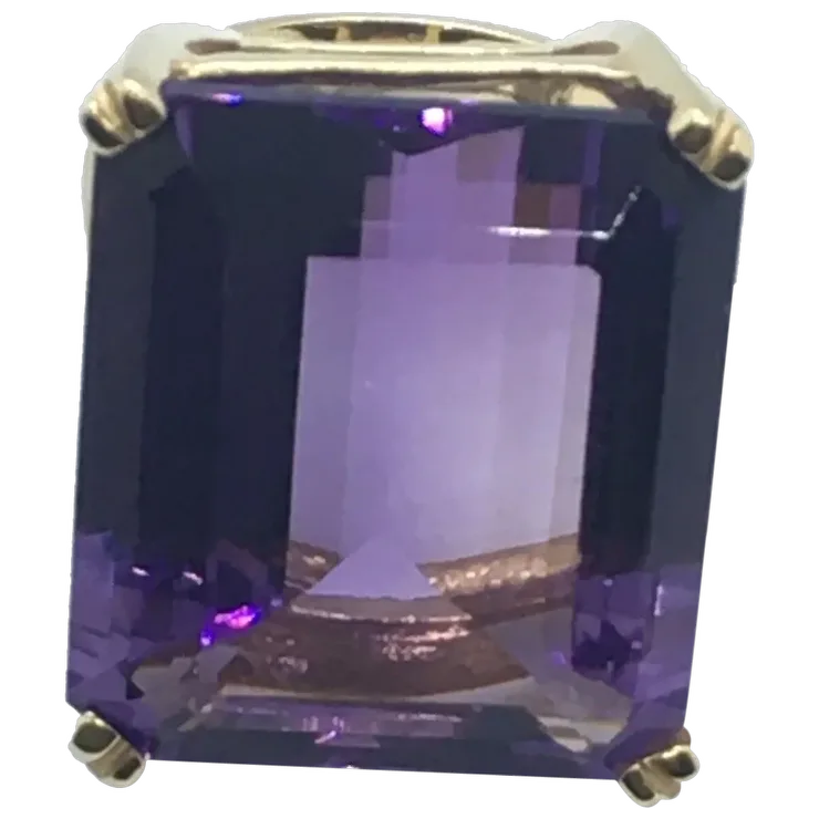 Ring with a large purple gemstone and gold setting on a white background