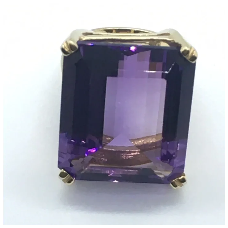 Amethyst gemstone in a gold setting on a white background
