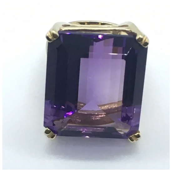Amethyst gemstone in a gold setting on a white background
