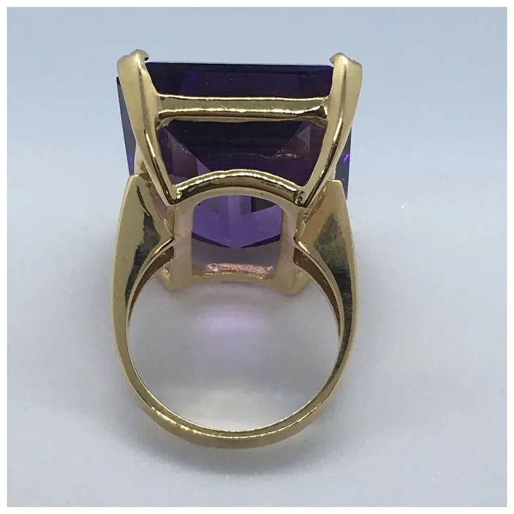 Gold ring with a purple gemstone on a light gray background