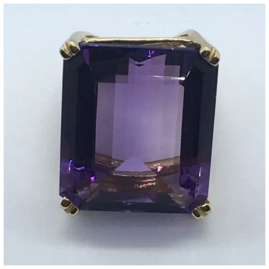 Gold ring with a large purple gemstone on a white background