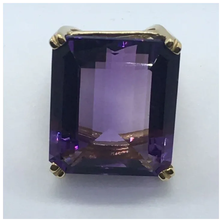 Gold ring with a large purple gemstone on a white background