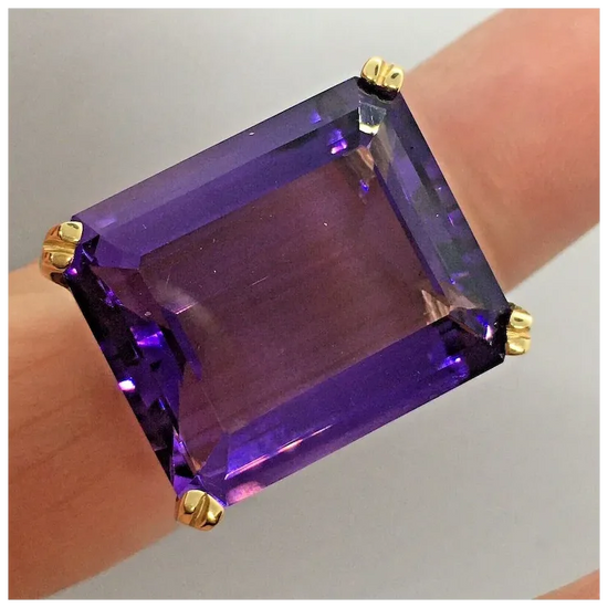 Purple gemstone ring with gold accents on a neutral background
