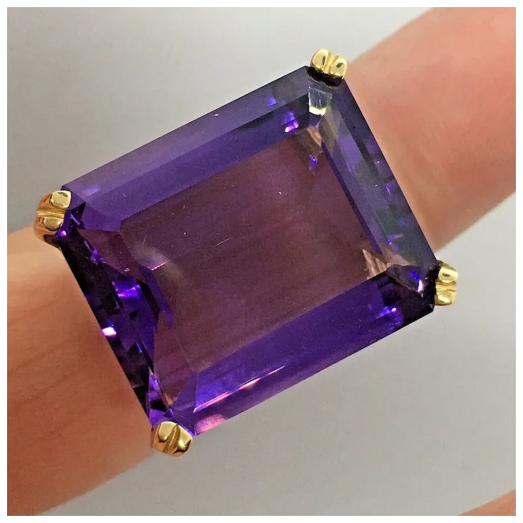 Purple gemstone ring with gold accents on a neutral background
