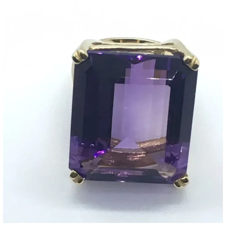 Gold ring with a large purple gemstone on a white background