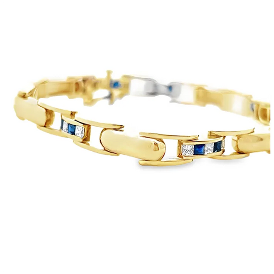 Gold bracelet with embedded blue and white gemstones on a white background