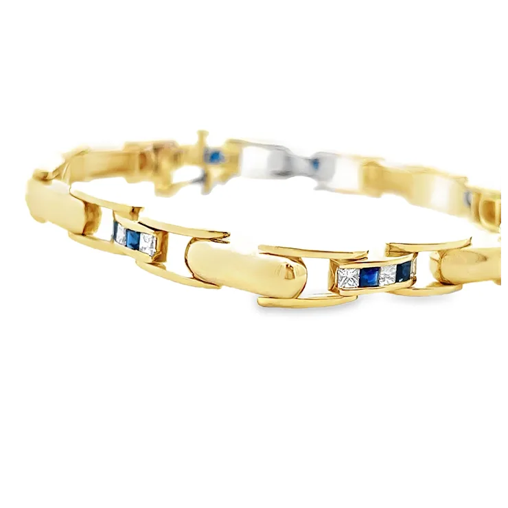 Gold bracelet with embedded blue and white gemstones on a white background