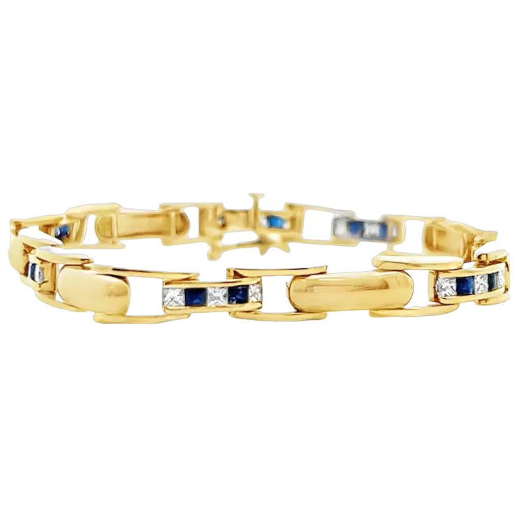 Gold bracelet with embedded blue and clear stones on a white background