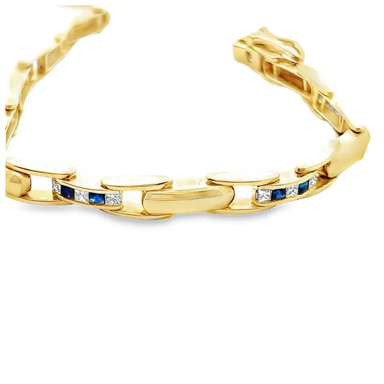 Gold bracelet with embedded blue and white stones on a white background