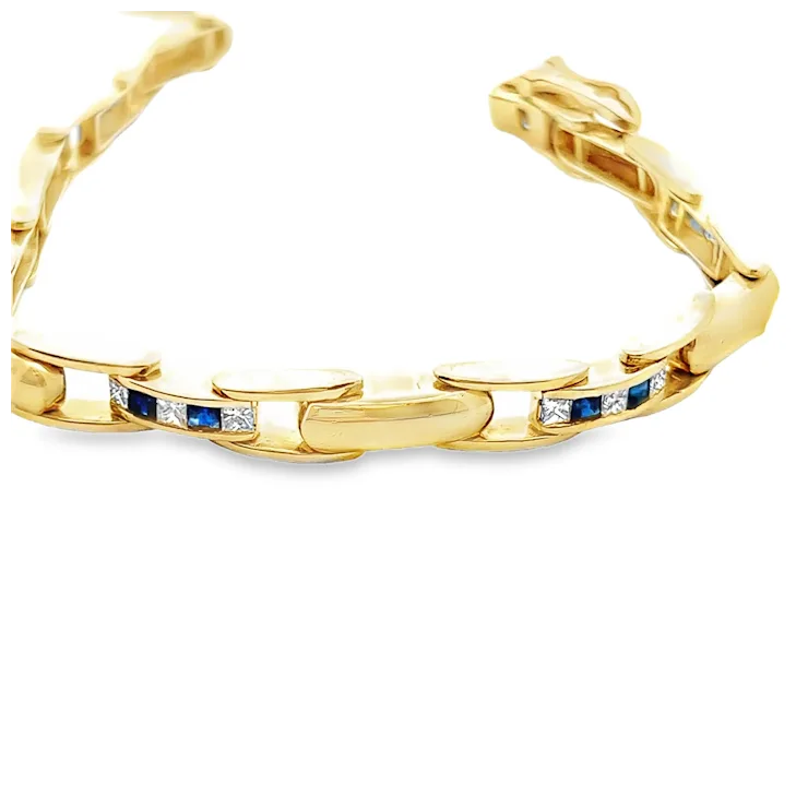 Gold bracelet with embedded blue and white stones on a white background