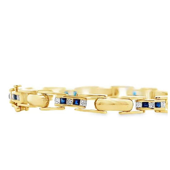 Gold bracelet with blue and white gemstones on a white background