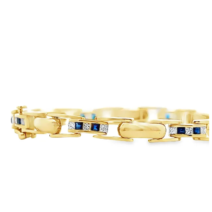 Gold bracelet with blue and white gemstones on a white background