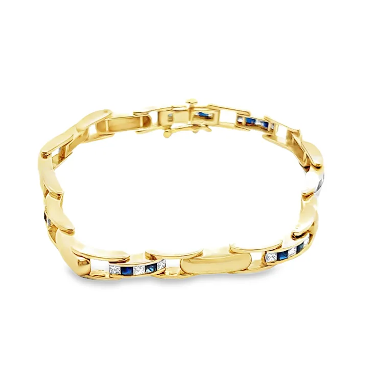 Gold bracelet with embedded blue and white stones on a white background