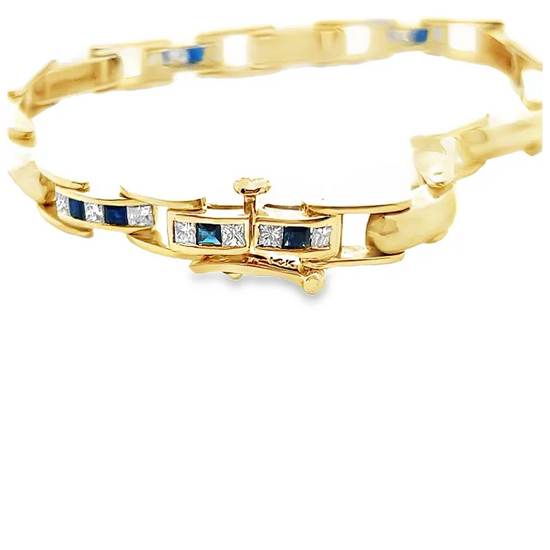 Gold bracelet with blue and clear gemstones on a white background