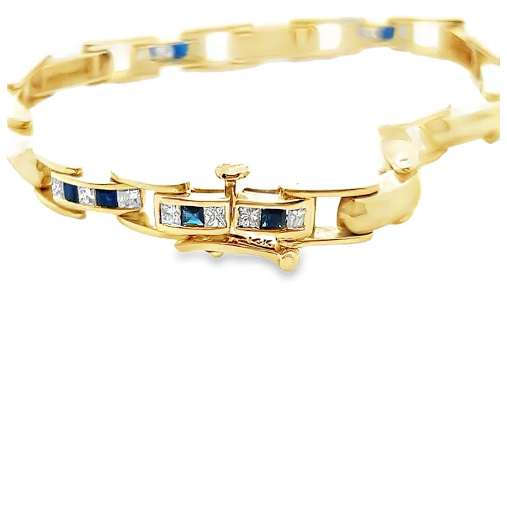 Gold bracelet with blue and clear gemstones on a white background