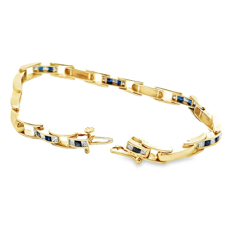 Gold bracelet with embedded blue and white stones on a white background