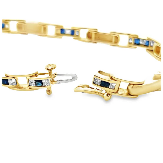 Gold bracelet with embedded blue and clear stones on a white background
