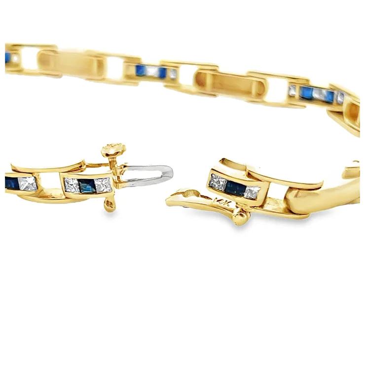Gold bracelet with embedded blue and clear stones on a white background