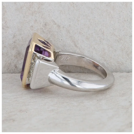 Silver ring with a purple gemstone on a textured surface