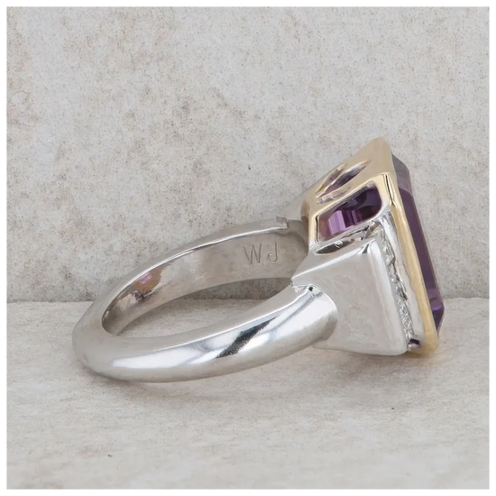 Silver ring with a purple gemstone on a textured surface