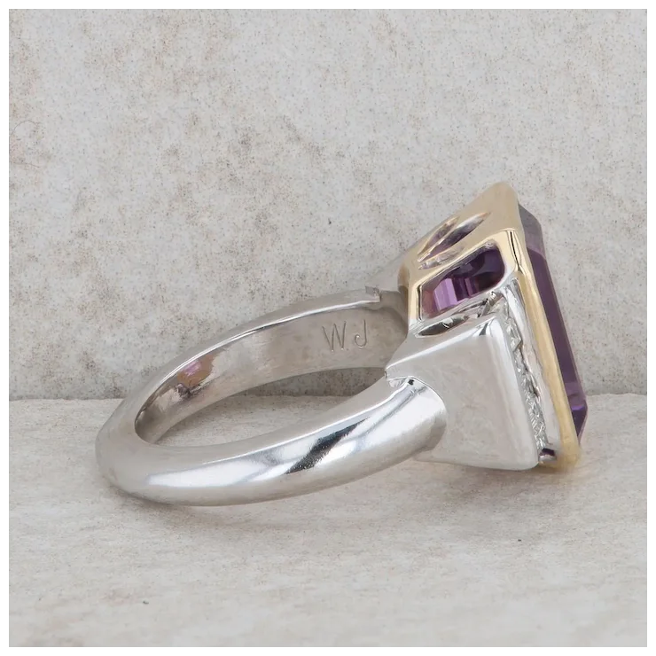 Silver ring with a purple gemstone on a textured surface