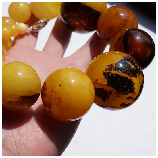 Close-up of amber beaded bracelet on a hand with a white background